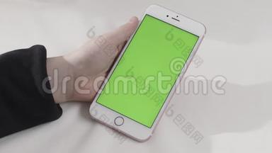 手持触摸绿色屏幕智能手机在白色背景。 库存录像。 手拿带chroma键的手机..